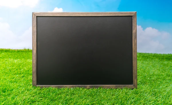 Blank black board on grass field — Stock Photo, Image