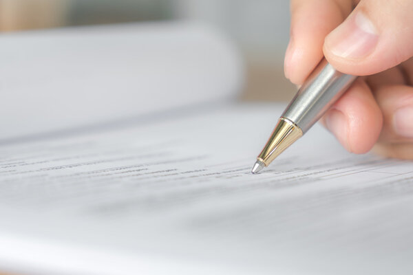 Рука с ручкой над анкетой
