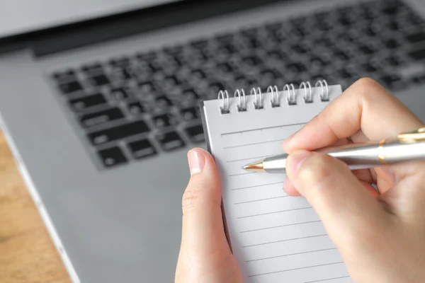 Frauenhand mit Bleistift über Laptop notiert — Stockfoto