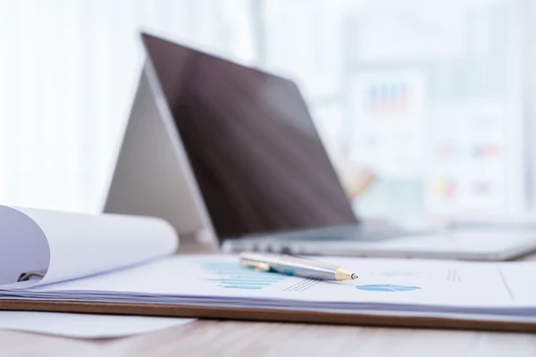 Cuadros financieros sobre la mesa con lapto — Foto de Stock