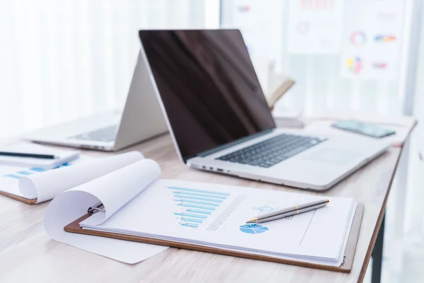 Cuadros financieros sobre la mesa con lapto — Foto de Stock