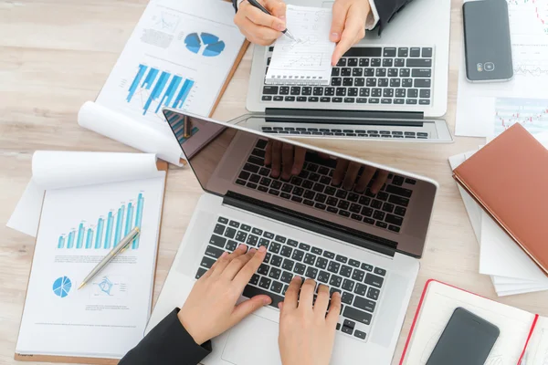 Gente de negocios usando el ordenador portátil y gráficos financieros en la reunión o — Foto de Stock