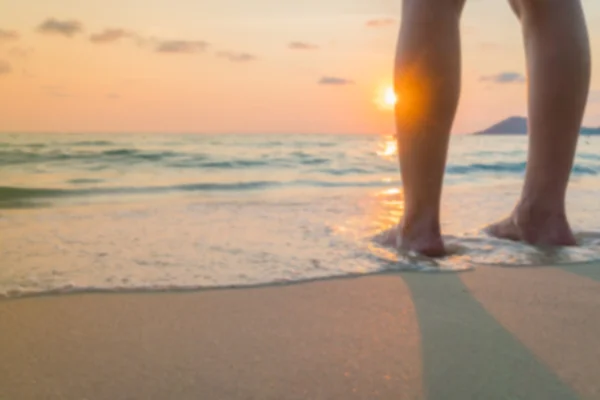 Abstrakte verschwommene Füße im Sand bei Sonnenuntergang — Stockfoto