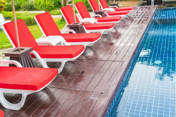 Belas cadeiras de praia com guarda-chuva em torno de natação ao ar livre — Fotografia de Stock