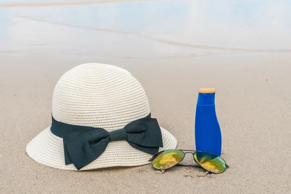Okulary przeciwsłoneczne, krem do opalania i kapelusz na piaszczystej plaży — Zdjęcie stockowe