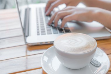 kahve fincanı ve dizüstü bilgisayar masada.