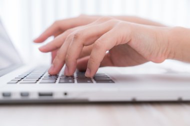 Laptop klavyesinde yazan kişi