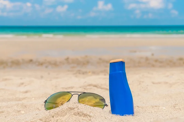 Sunglasses and sun cream on white  sand beach — Stock Photo, Image