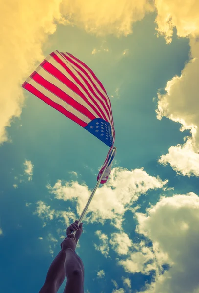 Bandera americana con estrellas y rayas sostienen con las manos contra blu — Foto de Stock