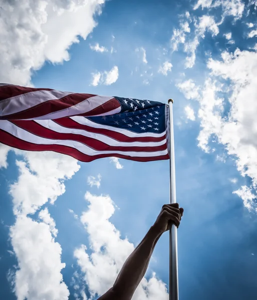 American flag with stars and stripes hold with hands against blu — Stock Photo, Image