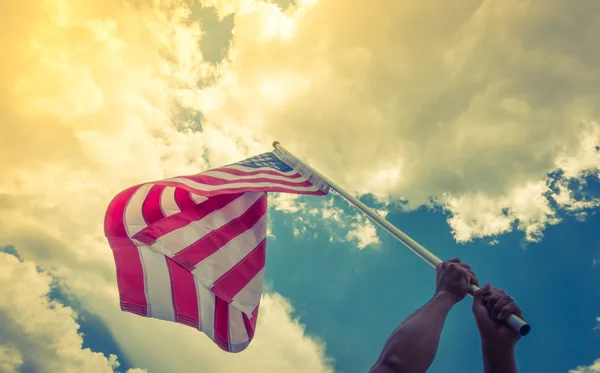 Bandera americana con estrellas y rayas sostienen con las manos contra blu — Foto de Stock