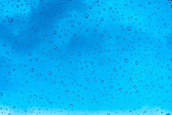 Gocce d'acqua sulla finestra di vetro sopra il cielo blu  . — Foto Stock
