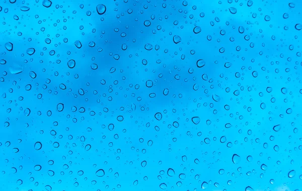 Gotas de agua en la ventana de cristal sobre el cielo azul  . —  Fotos de Stock