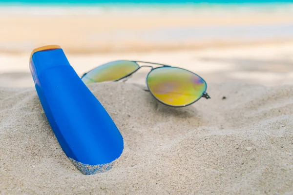 Zonnebrillen en zon crème op witte zand strand — Stockfoto