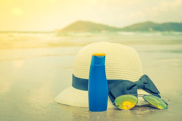 Sunglasses, sun cream and hat  on white  sand beach — Stock Photo, Image