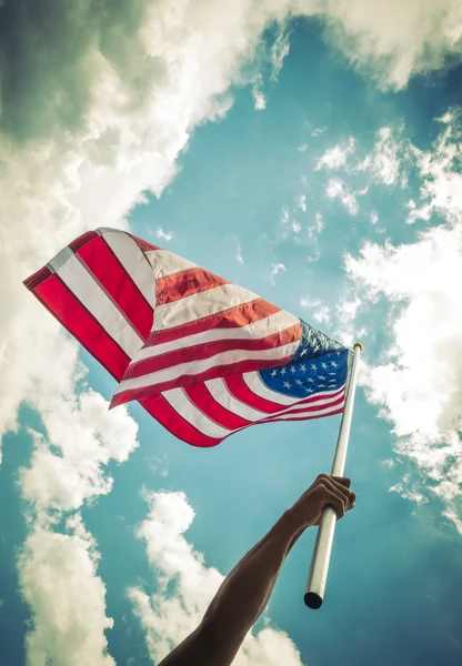 American flag with stars and stripes hold with hands against blu — Stock Photo, Image