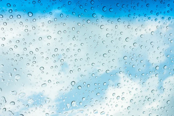 Des gouttes d'eau sur une fenêtre en verre au-dessus du ciel bleu  . — Photo