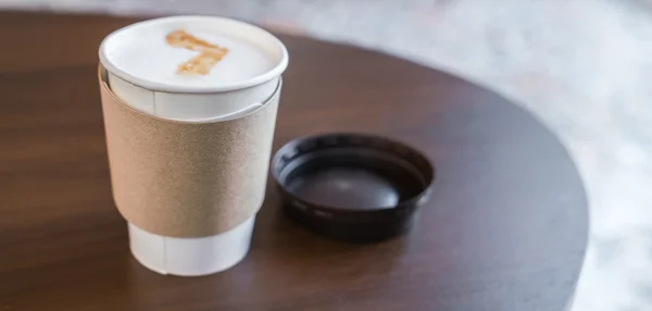 Papieren kopje koffie op houten tafel . — Stockfoto