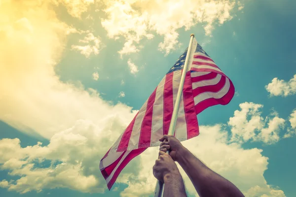 American flag with stars and stripes hold with hands against blu — Stock Photo, Image