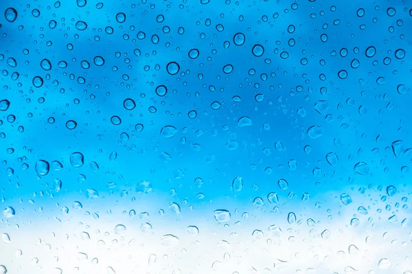 Des gouttes d'eau sur une fenêtre en verre au-dessus du ciel bleu  . — Photo