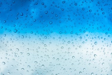 Mavi gökyüzü üzerinde cam pencere üstünde su damlaları .