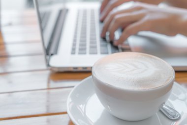 kahve fincanı ve dizüstü bilgisayar masada.