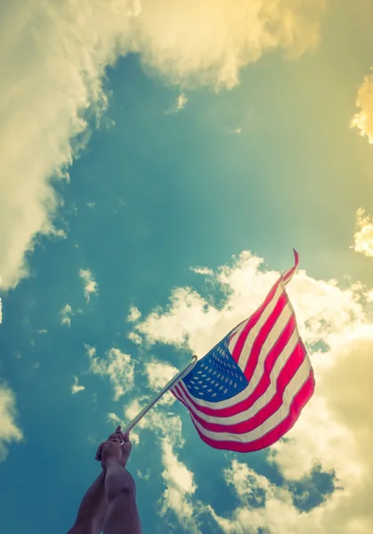 Bandera americana con estrellas y rayas sostienen con las manos contra blu — Foto de Stock