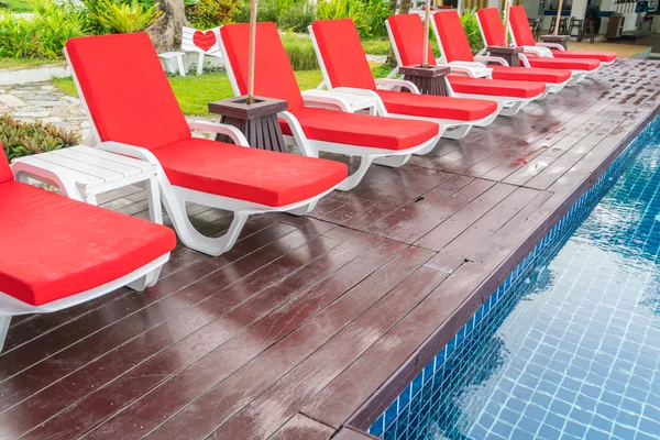 Belas cadeiras de praia com guarda-chuva em torno de natação ao ar livre — Fotografia de Stock