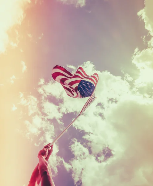 Bandera americana con estrellas y rayas sostienen con las manos contra blu — Foto de Stock