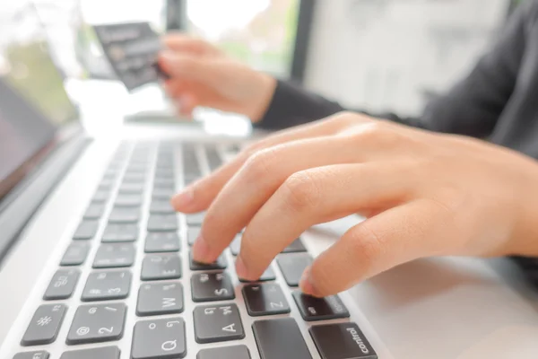 Mãos segurando um cartão de crédito e usando computador portátil para online — Fotografia de Stock