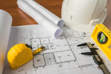 Bluepr üzerinde beyaz kask ve çizim araçları ile inşaat planları