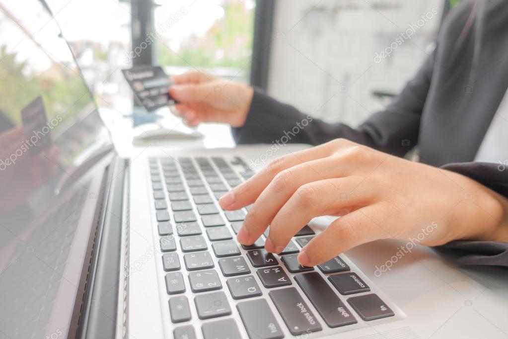 Hands holding a credit card and using laptop computer for online