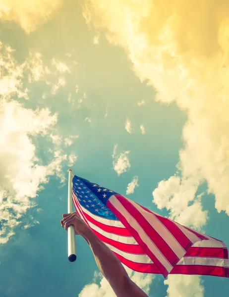 Bandera americana con estrellas y rayas sostienen con las manos contra blu — Foto de Stock