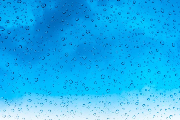 蓝蓝的天空上面的玻璃窗户上的水珠 . — 图库照片