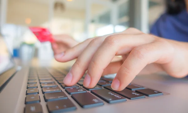 Mãos segurando um cartão de crédito e usando computador portátil para online — Fotografia de Stock