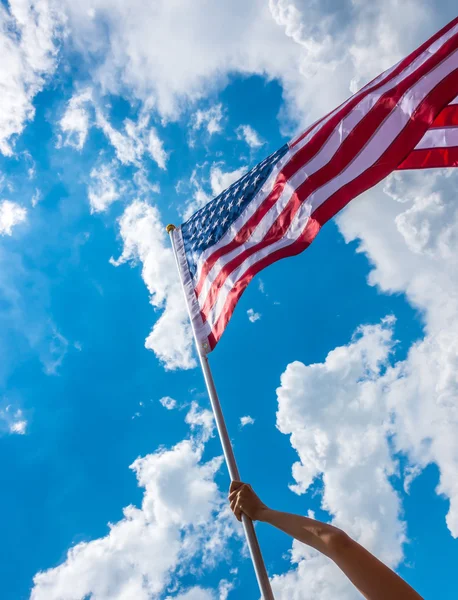American flag with stars and stripes hold with hands against blu — Stock Photo, Image