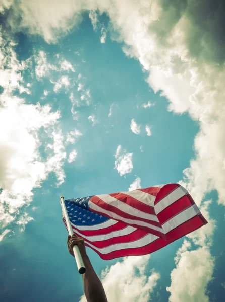 American flag with stars and stripes hold with hands against blu — Stock Photo, Image