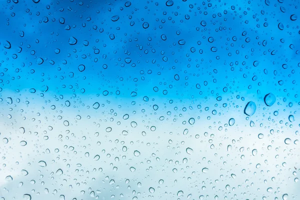 Gotas de água na janela de vidro sobre o céu azul  . — Fotografia de Stock