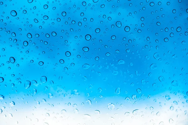 Des gouttes d'eau sur une fenêtre en verre au-dessus du ciel bleu  . — Photo