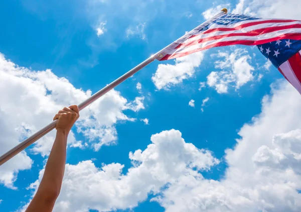 American flag with stars and stripes hold with hands against blu — Stock Photo, Image