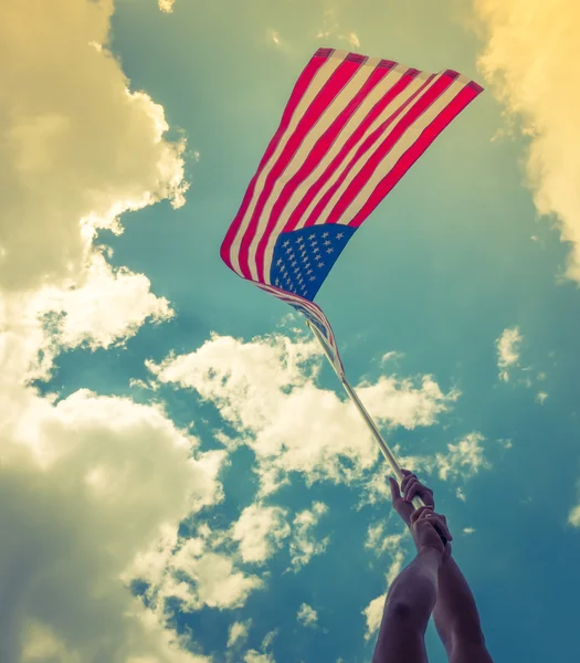 American flag with stars and stripes hold with hands against blu — Stock Photo, Image