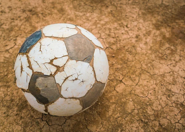 Old soccer ball on Dry and cracked ground texture . — Stock Photo, Image