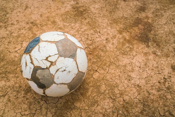 Old soccer ball on Dry and cracked ground texture . — Stock Photo, Image