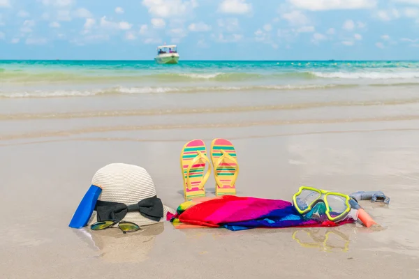 Zonnebril, zonnebrandcrème en hoed op witte zandstrand — Stockfoto