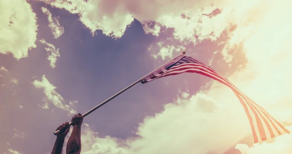 Bandera americana con estrellas y rayas sostienen con las manos contra blu — Foto de Stock