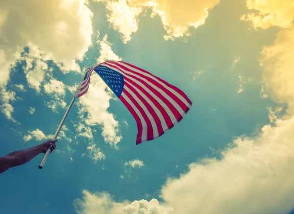 American flag with stars and stripes hold with hands against blu — Stock Photo, Image