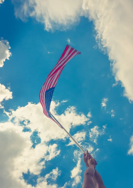 American flag with stars and stripes hold with hands against blu — Stock Photo, Image