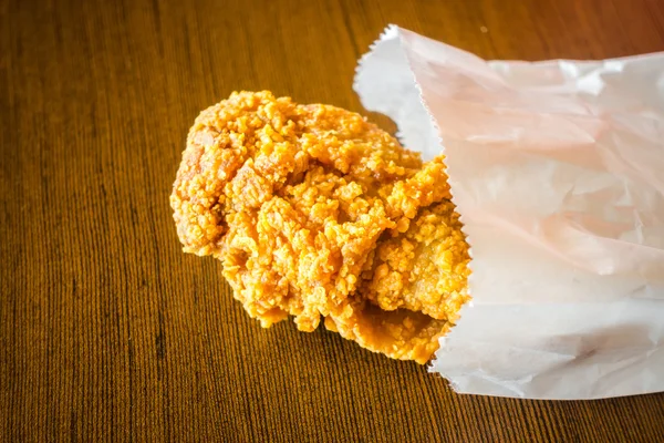 Ayam goreng Wings dalam kantong kertas di atas meja kayu  . — Stok Foto