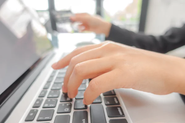 Hände, die eine Kreditkarte halten und Laptop-Computer für Online- — Stockfoto