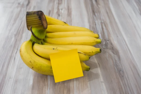 Banana com nota pegajosa na mesa de madeira  . — Fotografia de Stock